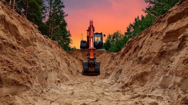 An excavator digging a trench on a land development project in Modesto, CA