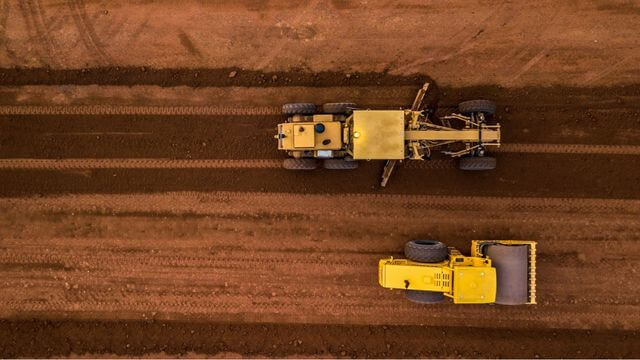 A grader and a soil compactor grading some land.