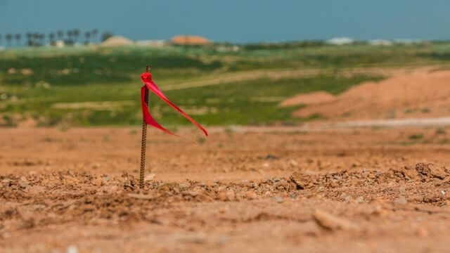 A construction stake with a red ribbon on a project.